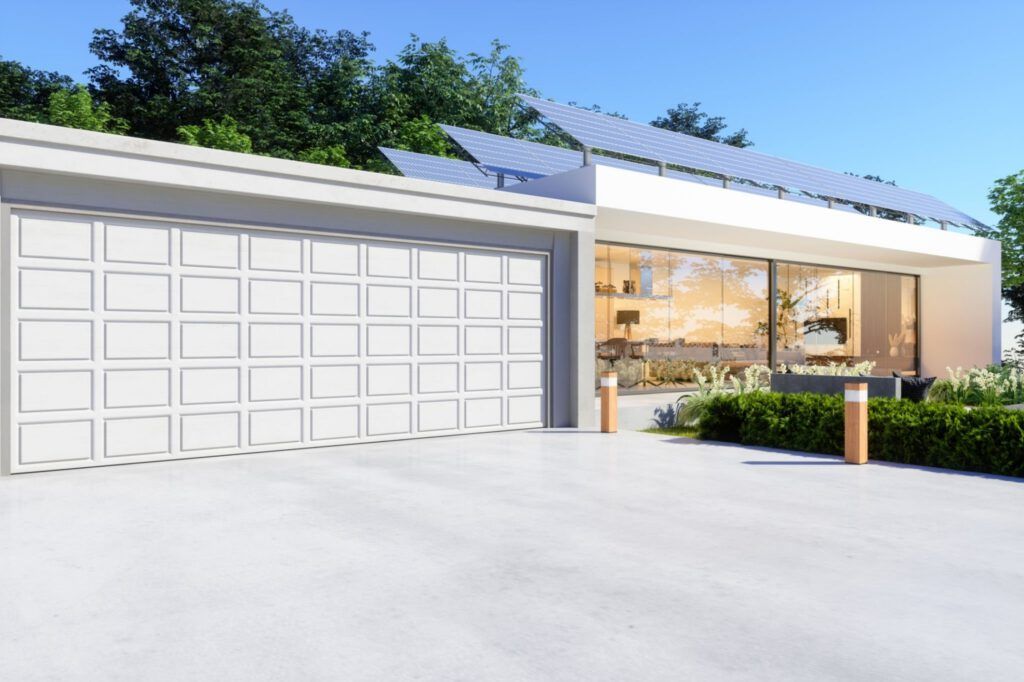 A modern house with a large garage door and solar panels on the roof.