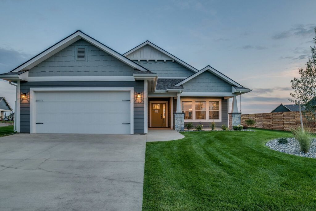 A large house with a white garage door is sitting on top of a lush green lawn.