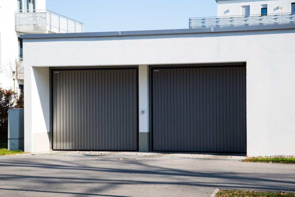 A white house with a gray garage door and a balcony.