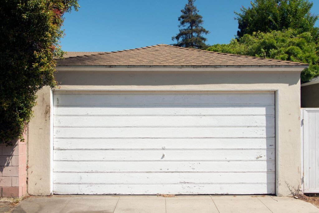 A white garage door is open in front of a house.