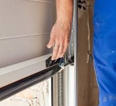 A person is opening a garage door with their hand.