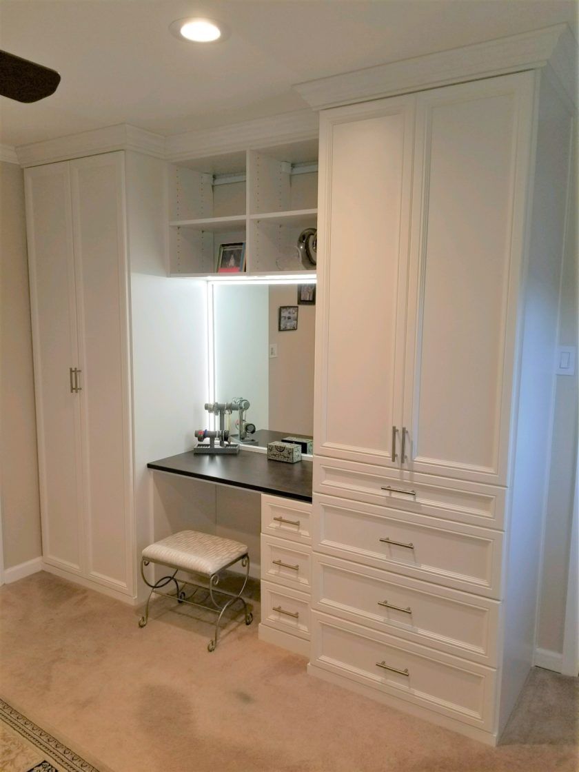 Livingston, NJ built-in unit incorporates a vanity with dimmable LED lighting, drawers for folded items and hang sections behind doors.