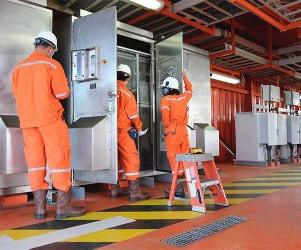 A Group Of Men In Orange Jumpsuits Are Working On A Machine — RAFFBRO Electrical Solar & Air Conditioning In Wodonga, VIC