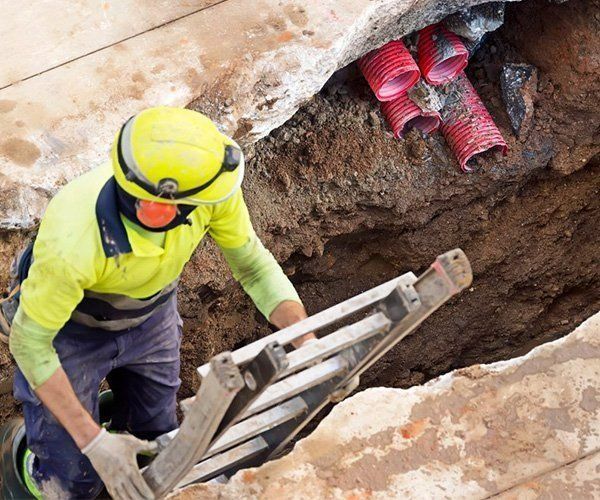 A Man Is Using A Ladder To Get Out Of A Hole — RAFFBRO Electrical Solar & Air Conditioning In Wodonga, VIC