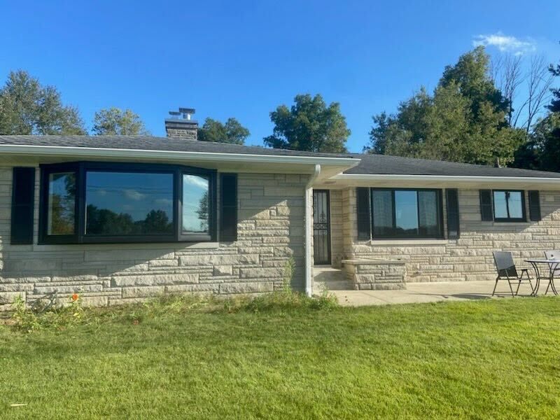 A brick house with black shutters and a large window