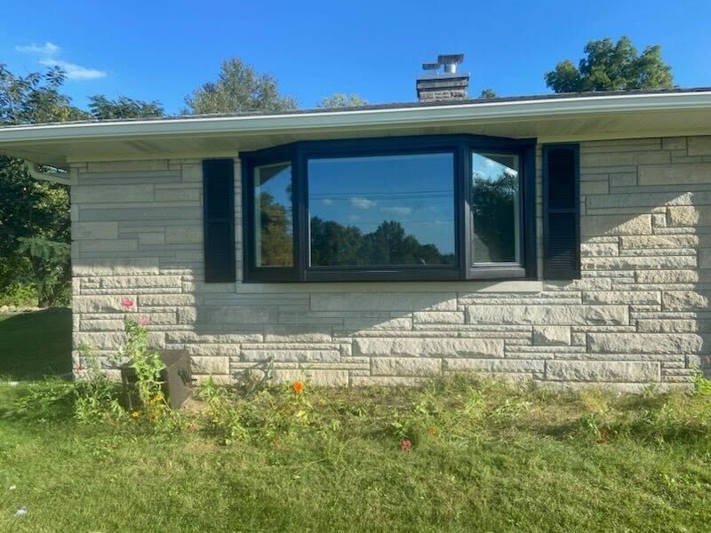 A brick house with a large bay window and black shutters.