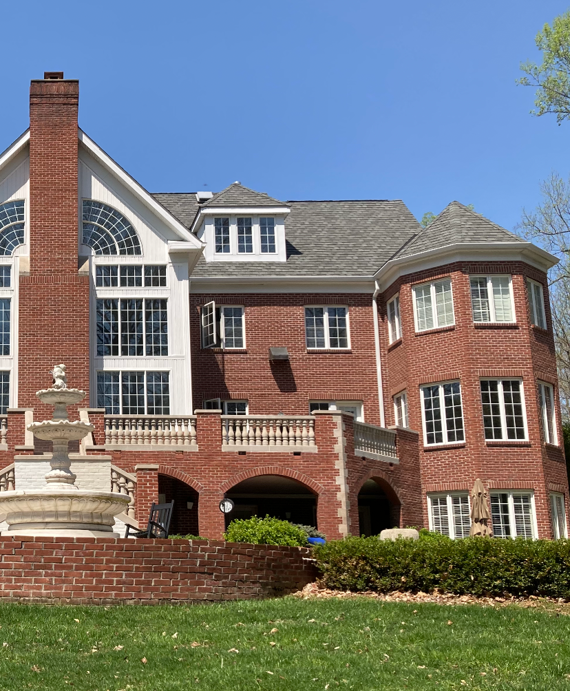 A large brick house with a fountain in front of it
