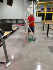 A man in a red shirt is cleaning a bowling alley floor