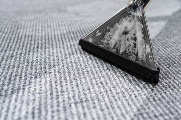 A close up of a vacuum cleaner cleaning a carpet.