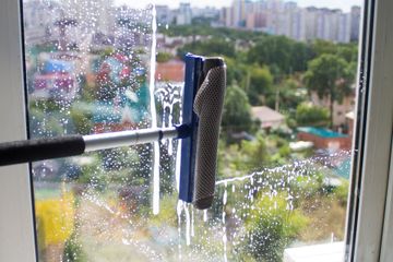 A person is cleaning a window with a squeegee.