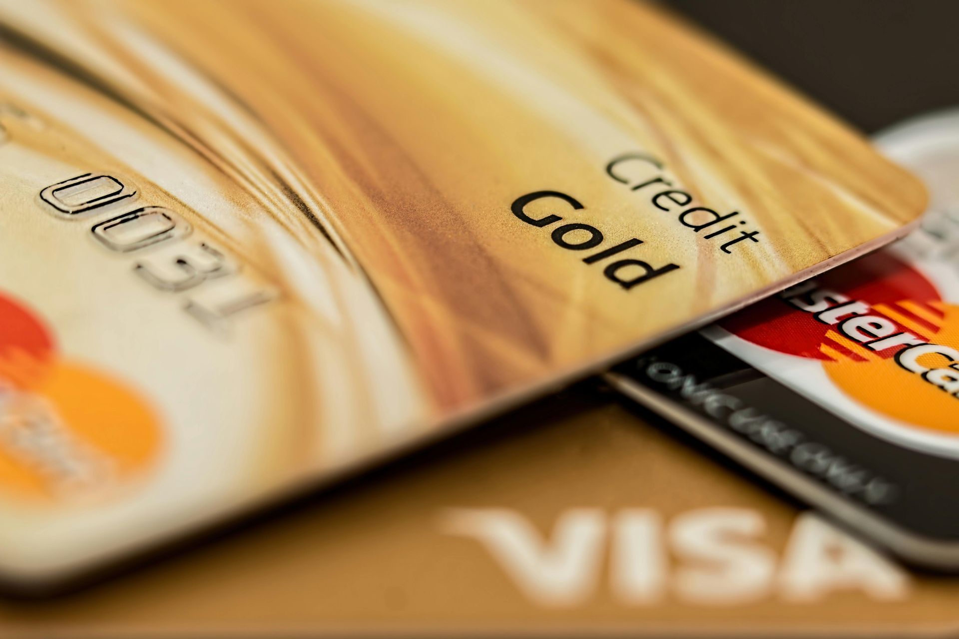 Close-up of gold credit cards with logos for Mastercard and Visa visible.