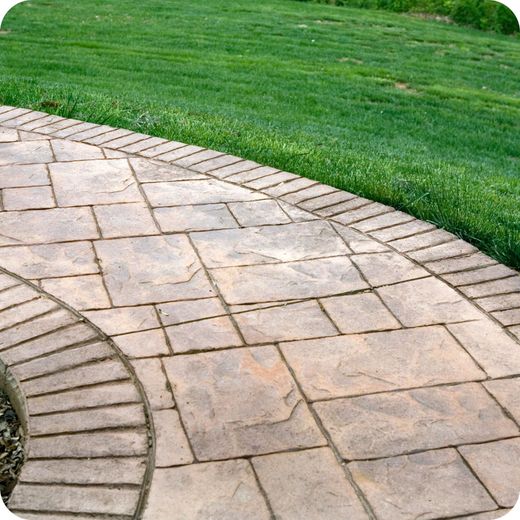 A brick walkway going through a grassy field