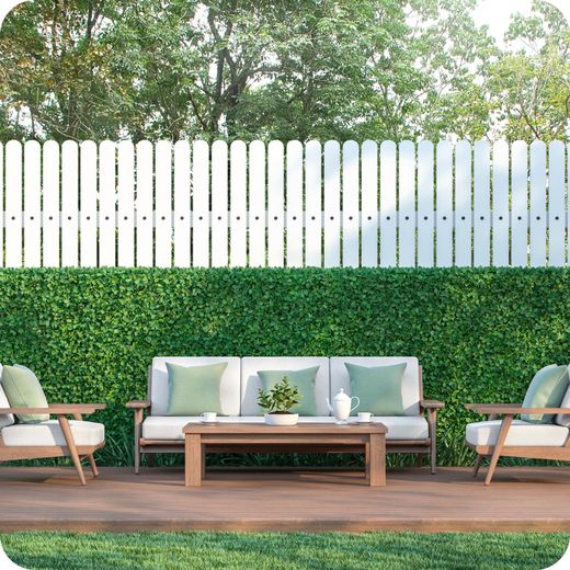 A patio with a couch , chairs and a table in front of a white fence.