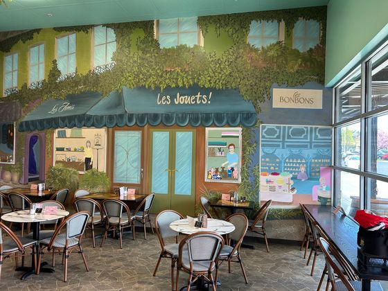 A restaurant with tables and chairs and a sign that says it 's deserts