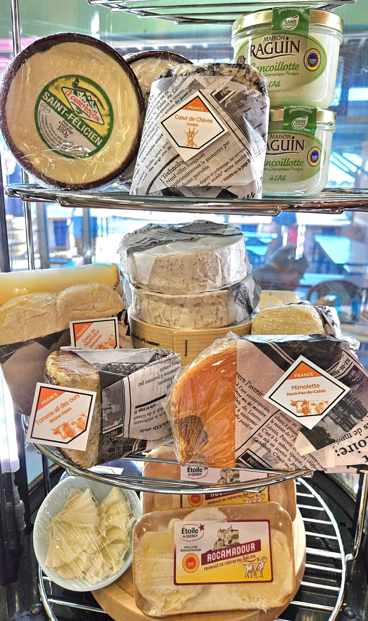 A variety of cheeses are stacked on top of each other on a shelf.