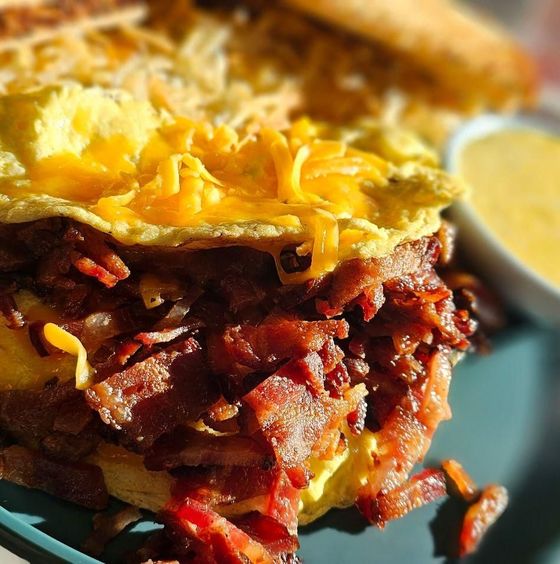 A close up of a sandwich with bacon and cheese on a plate