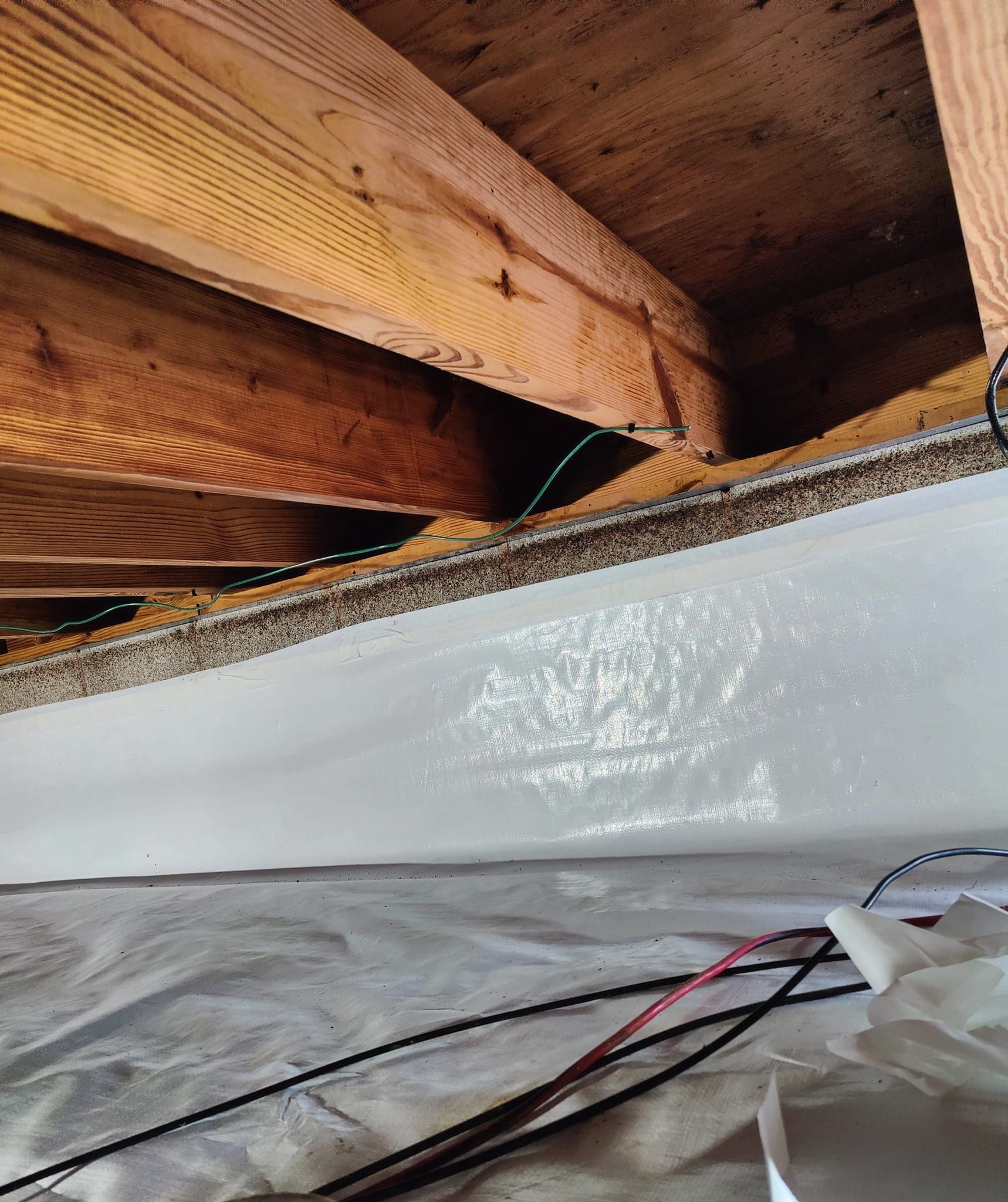 A close up of a ceiling with wooden beams and electrical wires.
