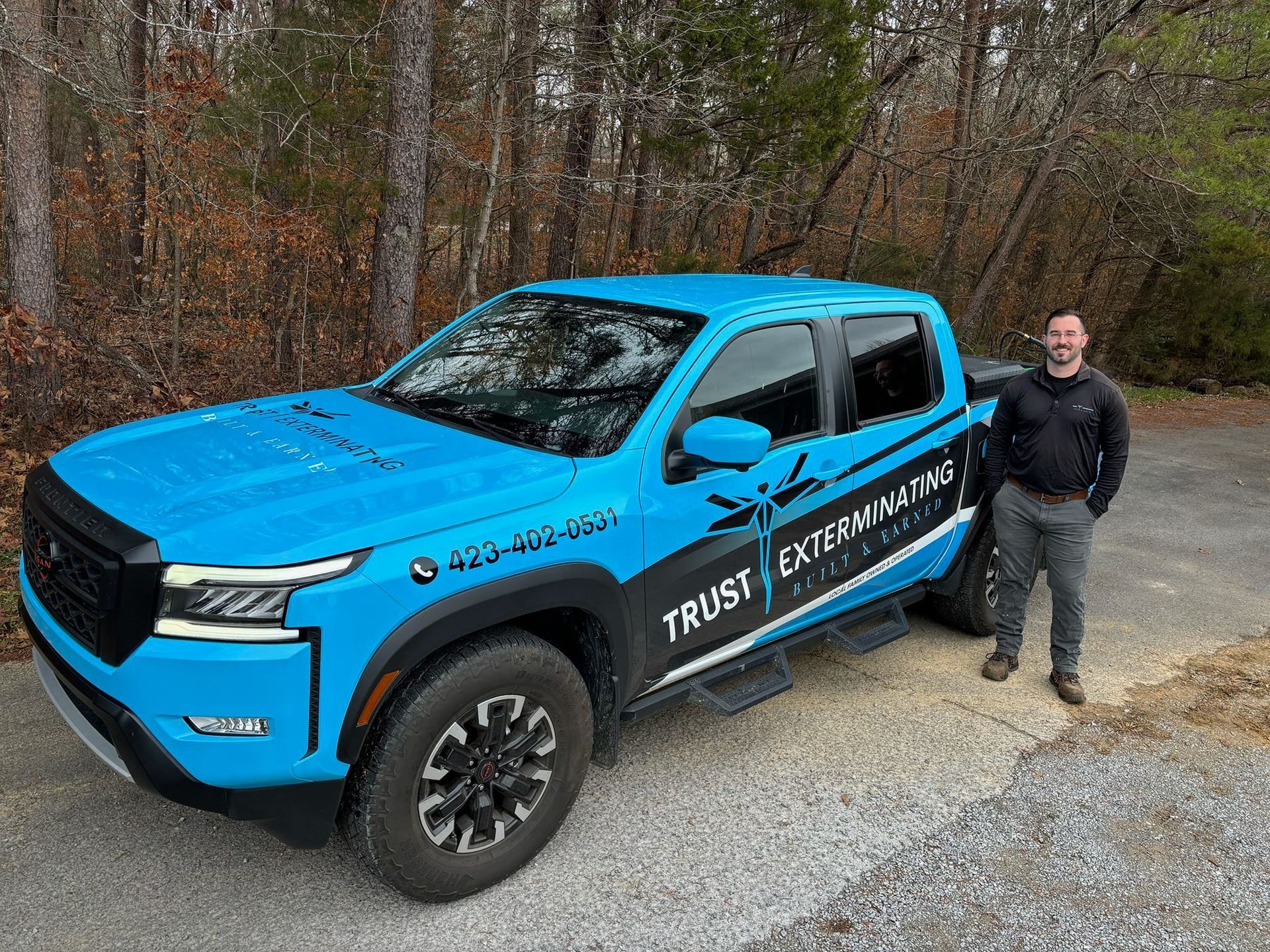A man is standing next to a blue truck.