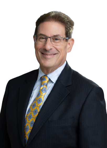 Smiling man in a suit and tie, wearing glasses. He has light skin, brown hair, and a dark red tie.