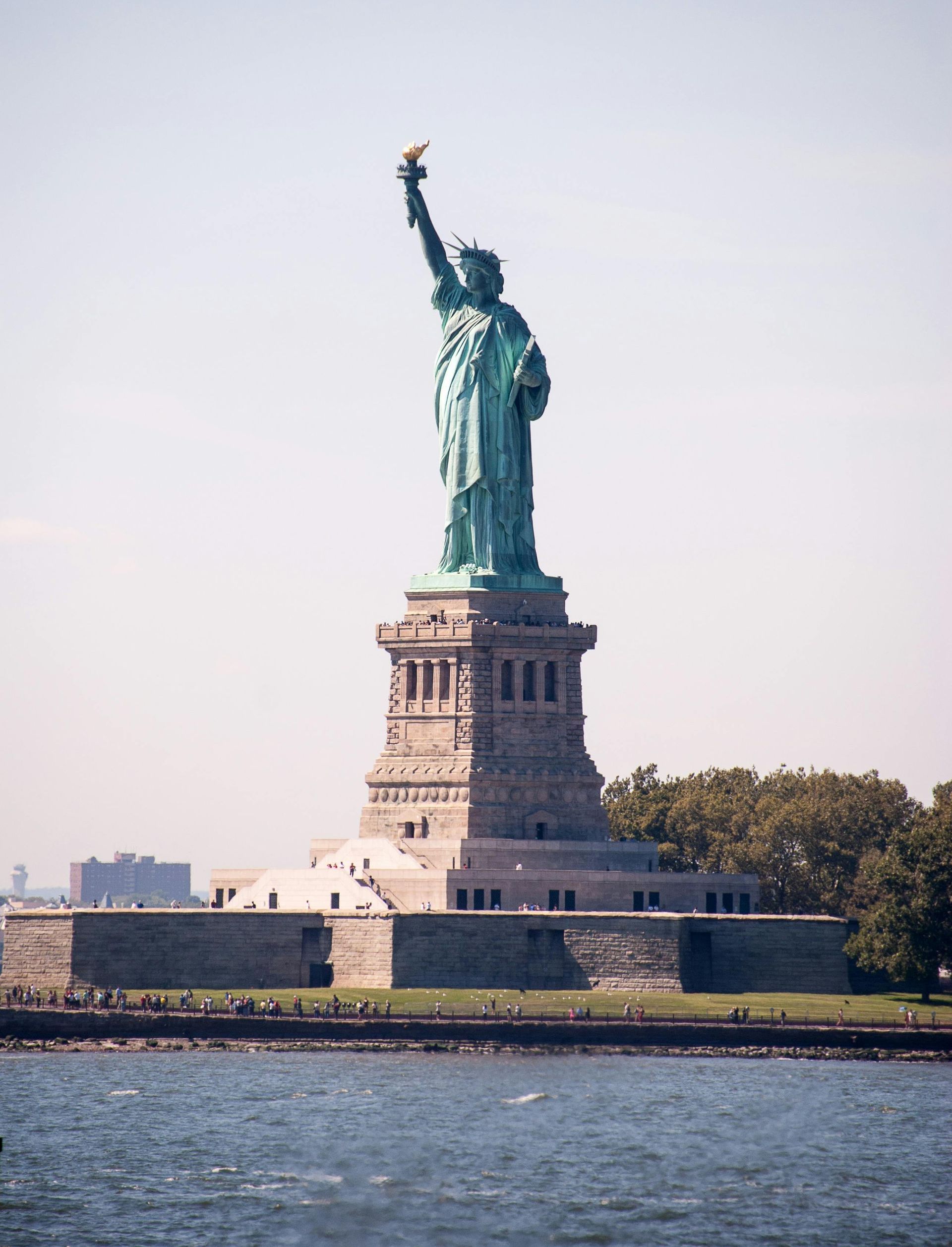 A woman wearing a straw hat and a blue dress is standing on a beach.
