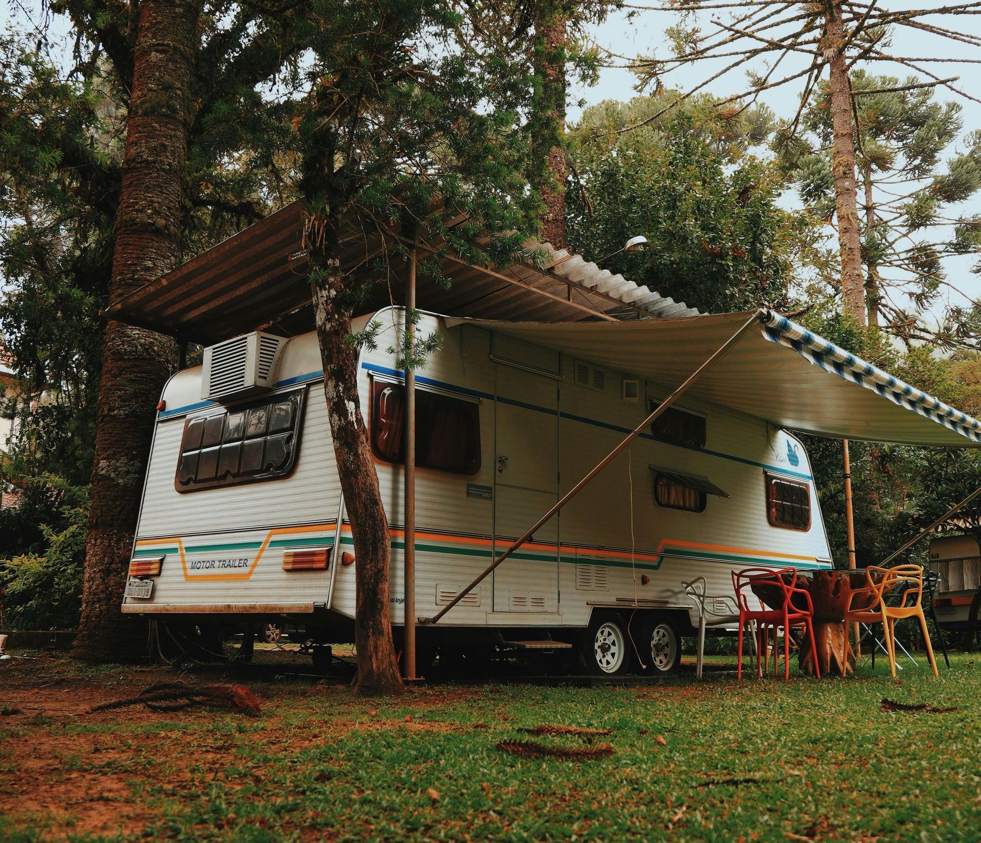 A rv is parked in a grassy field next to trees.