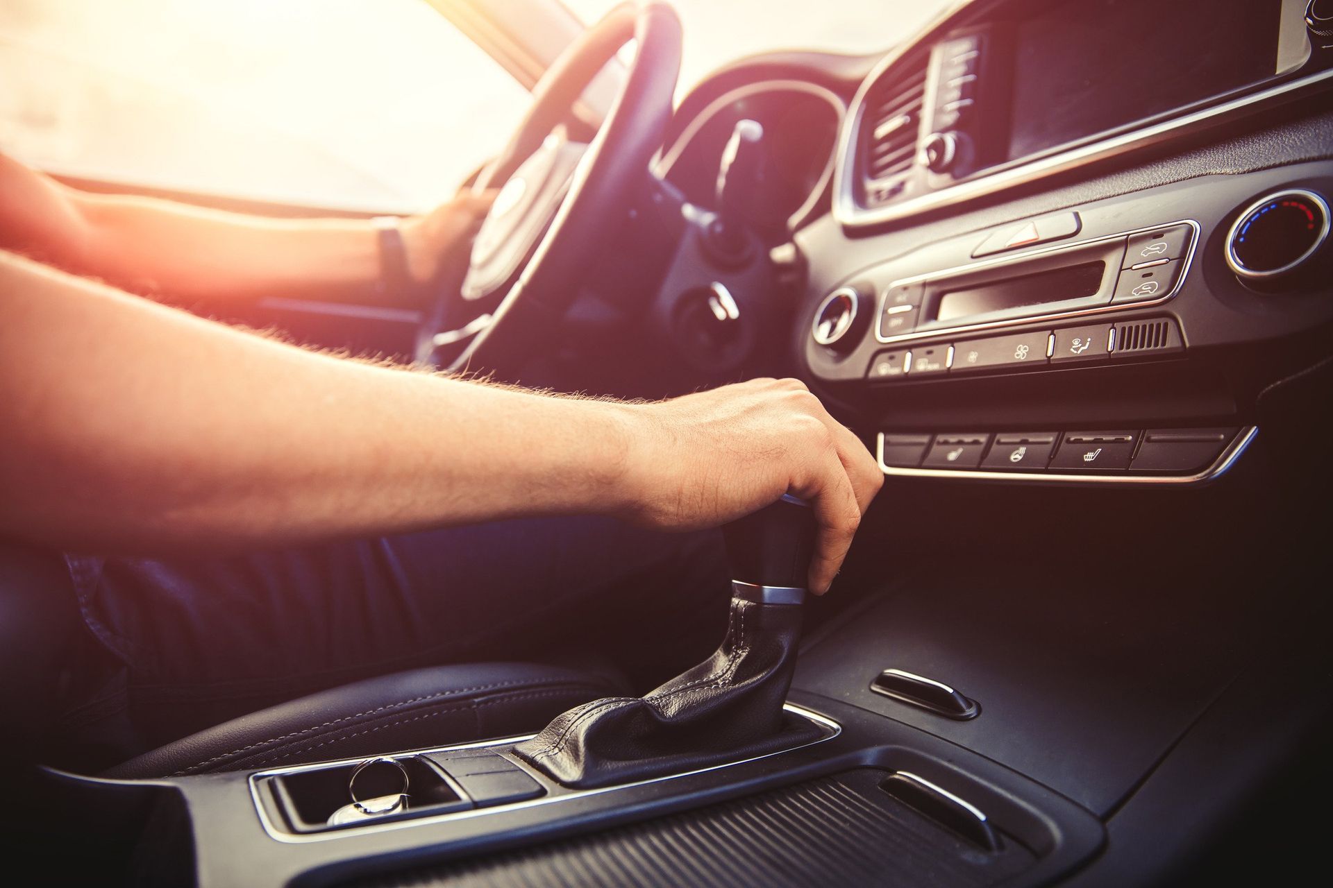 A man is driving a car and changing gears.