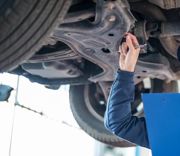 A man is working under a car with a wrench.