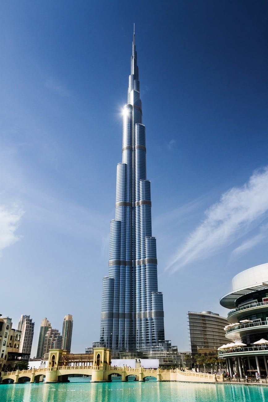 Burj Khalifa rising above fountains in Dubai under a clear blue sky