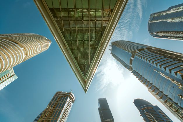 Upward view of modern skyscrapers framing a bright blue sky