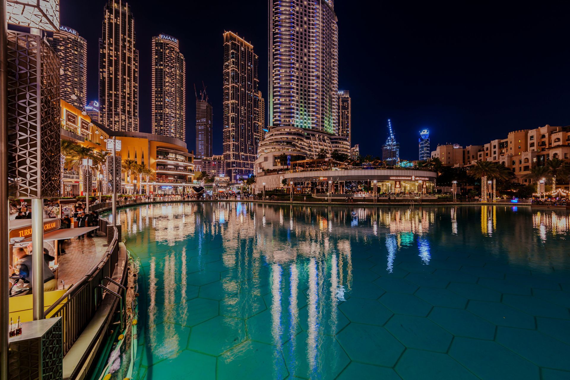 Nighttime marina with turquoise water reflecting illuminated high-rise towers and waterfront buildings
