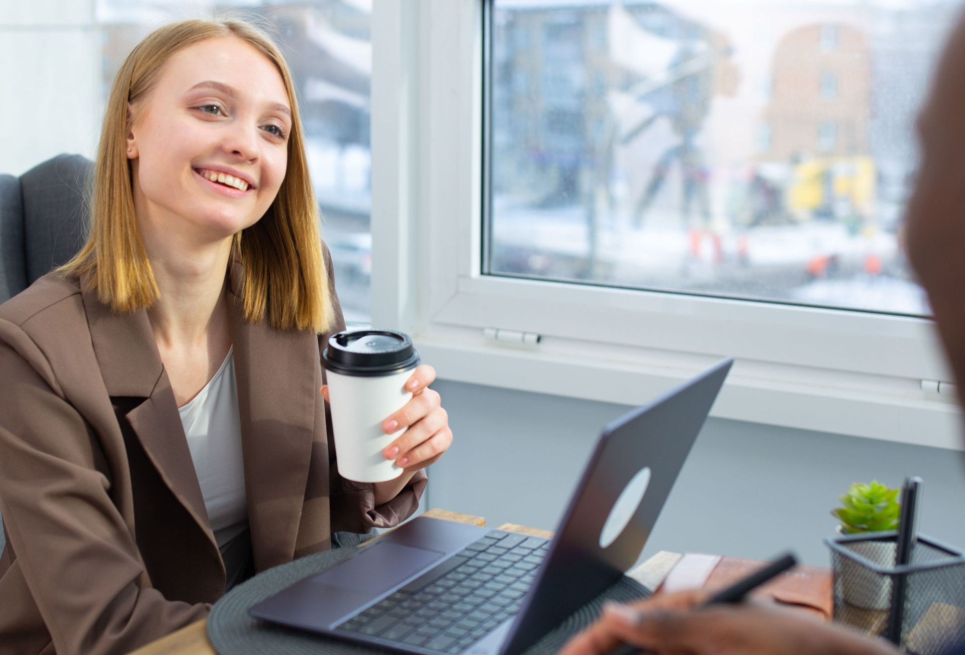 Smiling person in a blue shirt shaking hands in a bright office setting