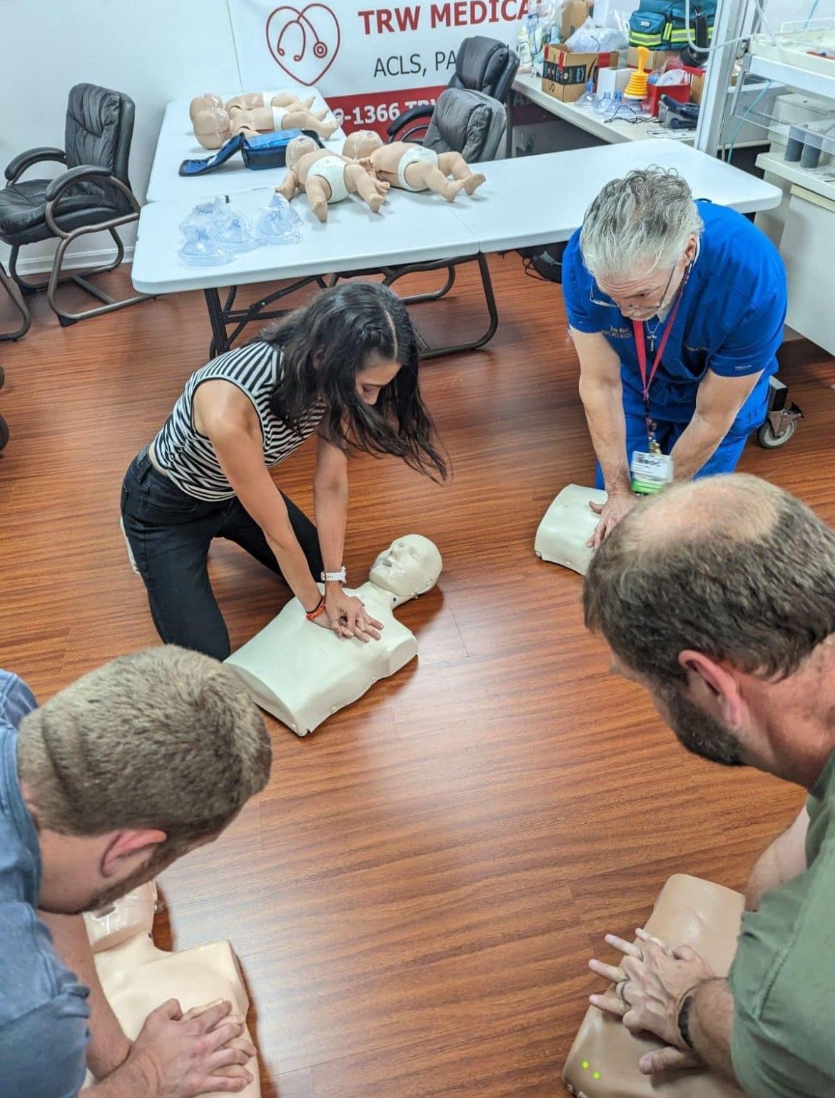 A group of people are practicing a cpr on a mannequin.