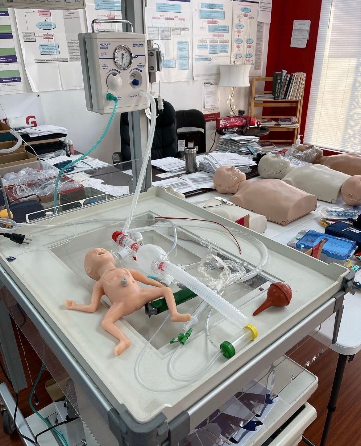 A baby mannequin is laying on a table with a hose attached to it.