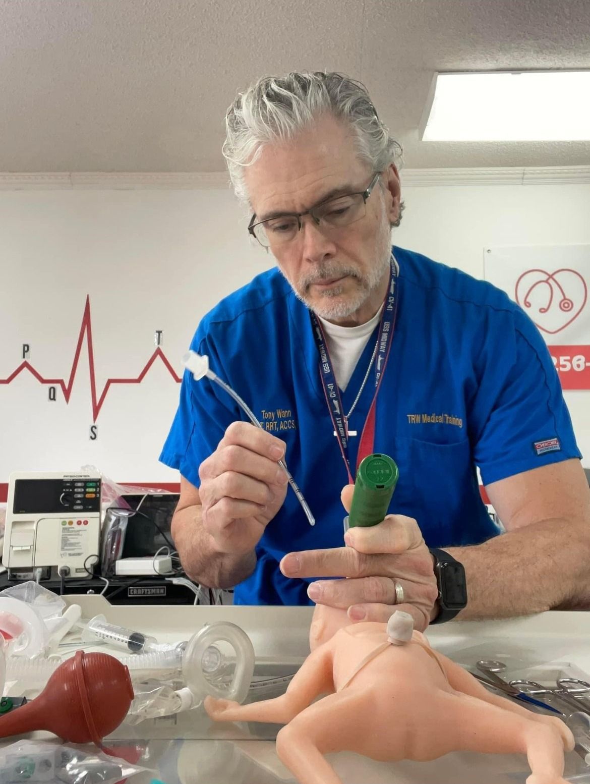 A man in a blue scrub is working on a doll