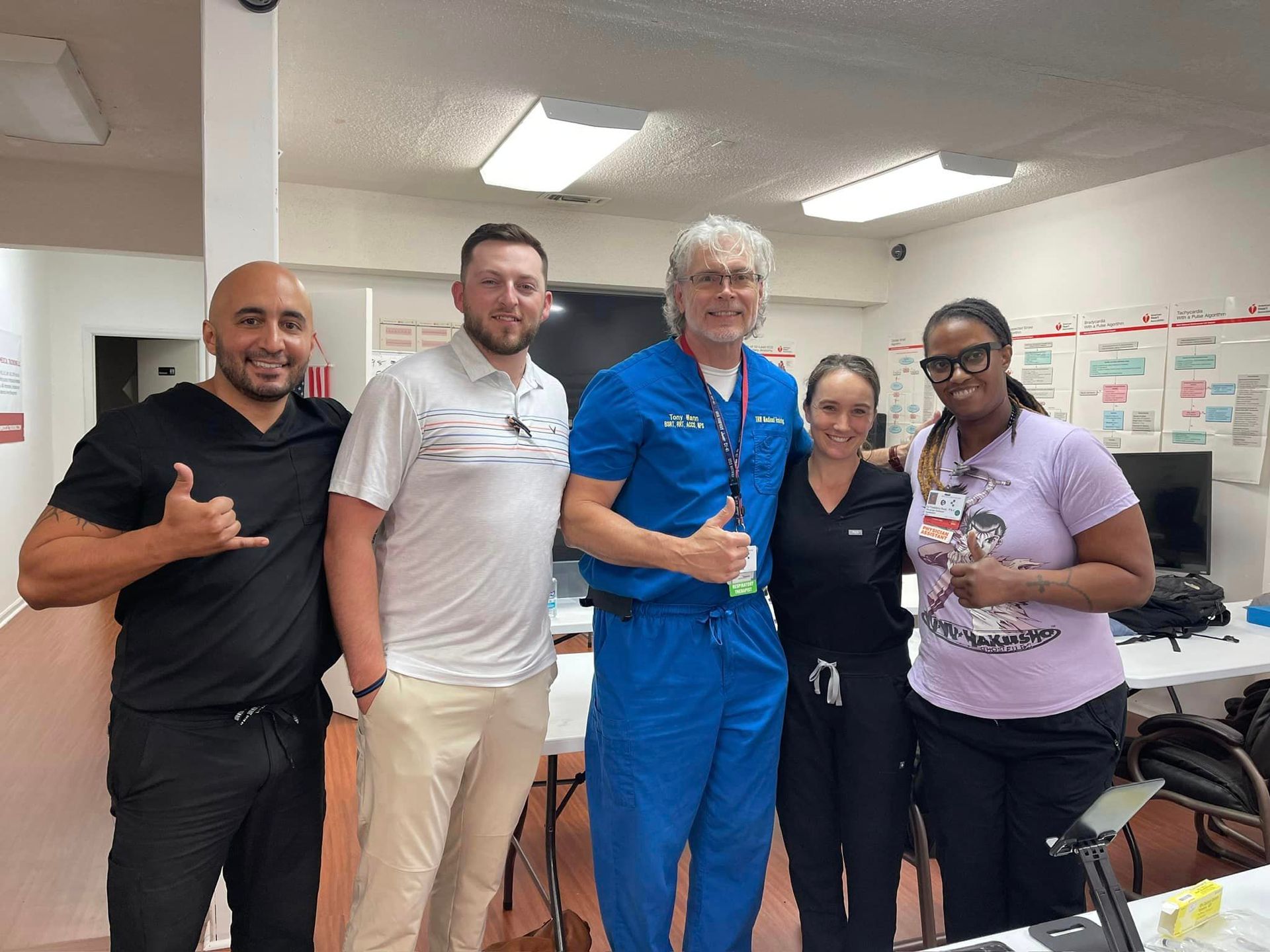 Five people smiling, standing indoors. One gives the 