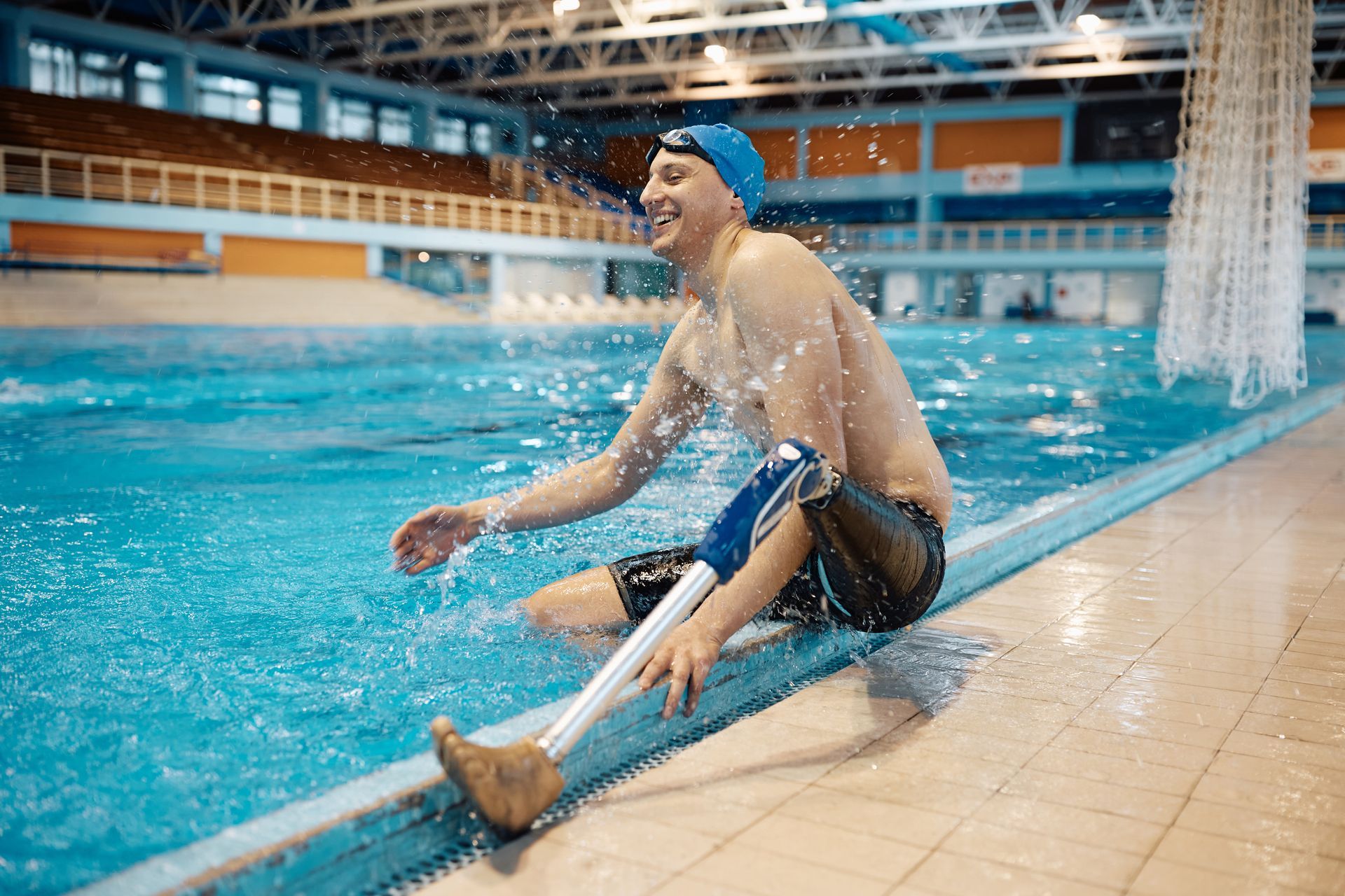Swimmer sitting on the edge of the pool with a swimming prosthetic.