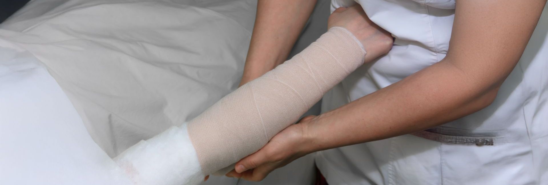 Eine Person wickelt den Arm einer anderen Person in einen Verband.