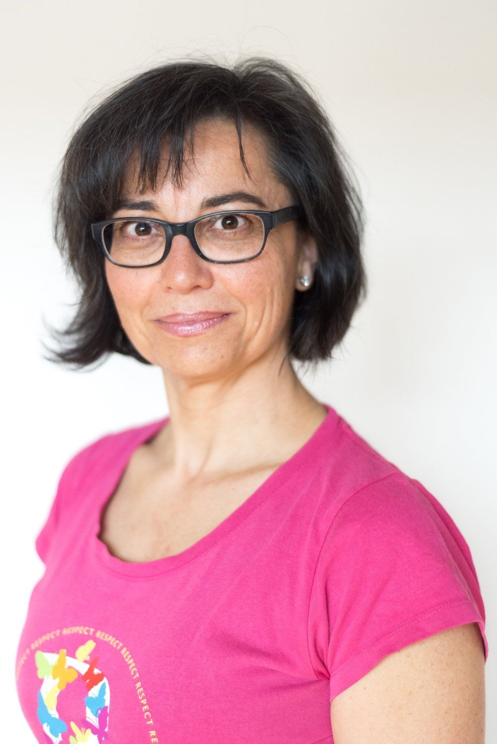 Die Frau trägt eine Brille und ein rosa Hemd