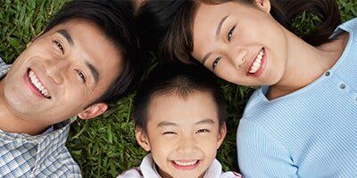 Couple With Son Lying On Grass Elevated View — Dental Care in Denver, CO