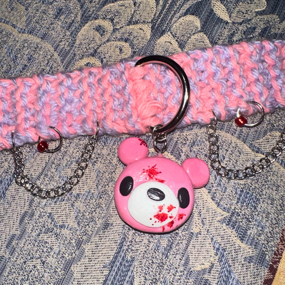 A pink and purple choker with a pink teddy bear pendant