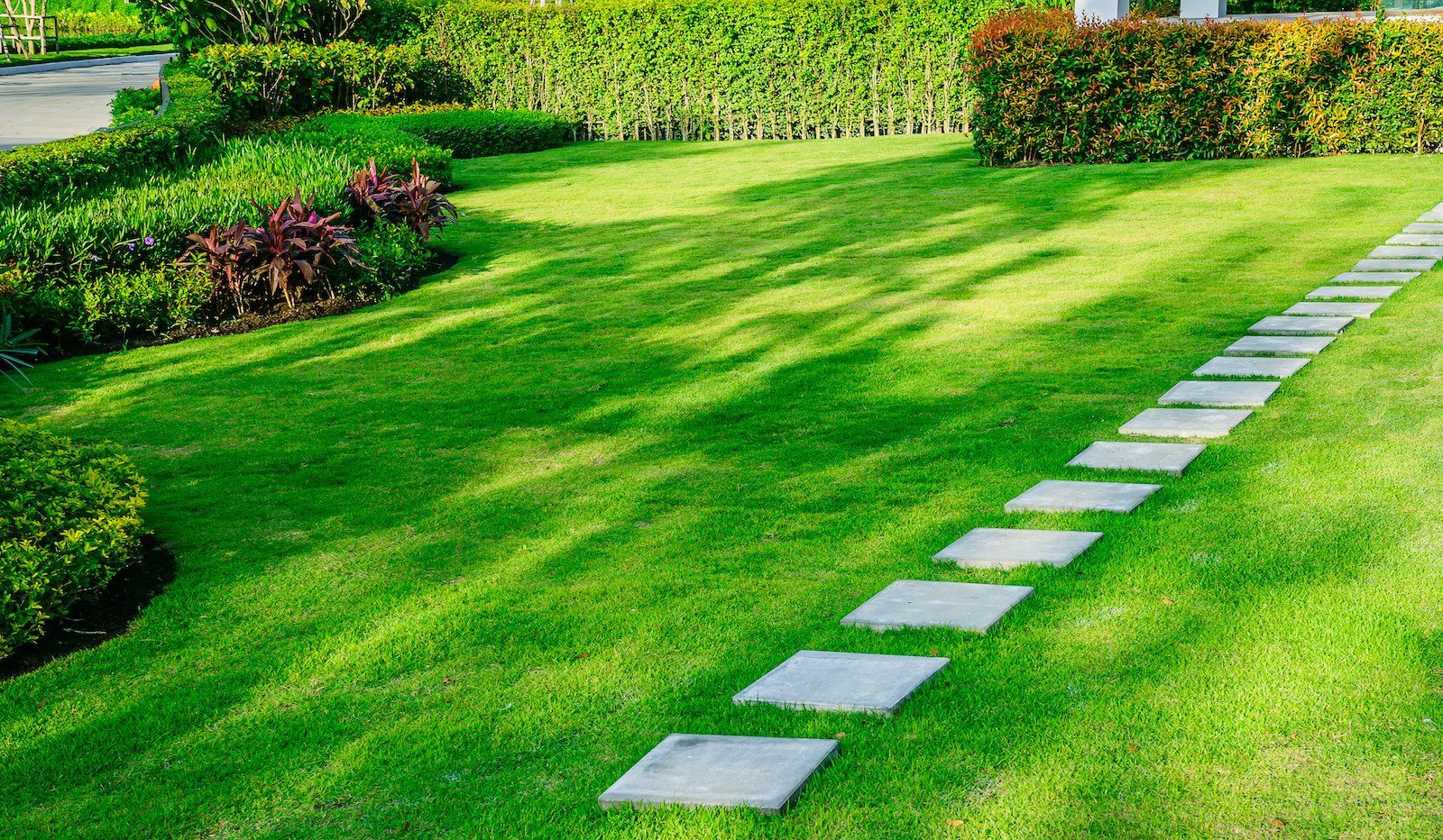 A stone walkway leading through a lush green lawn.