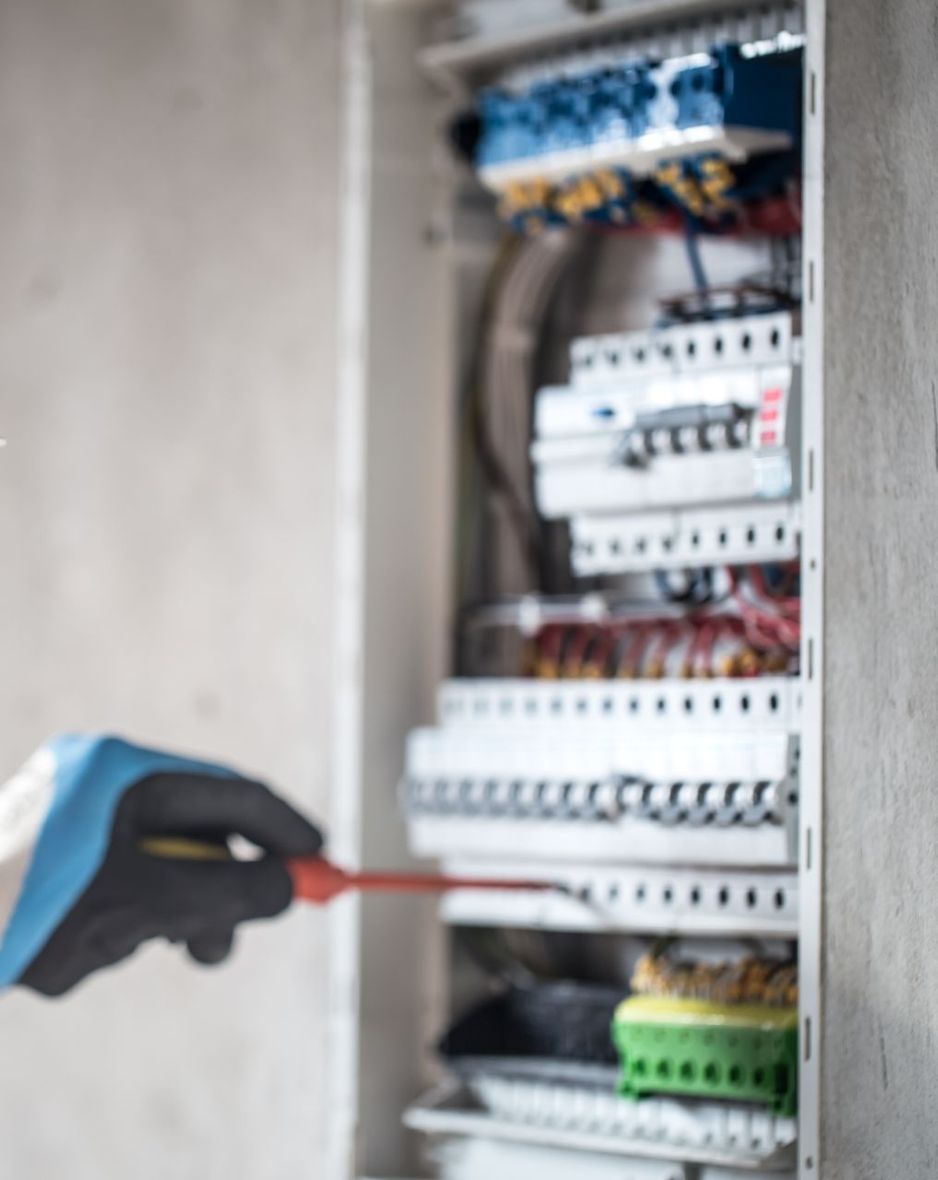 Una persona está usando un destornillador para arreglar una caja eléctrica.