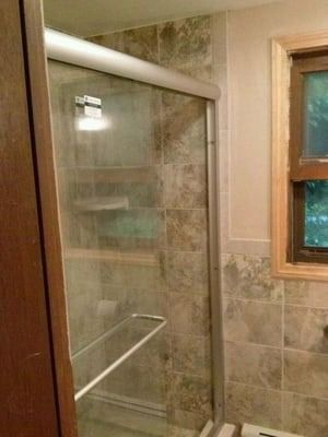 A bathroom with a glass shower door and a window.