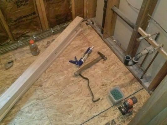 A snake is laying on a wooden floor next to a hammer.