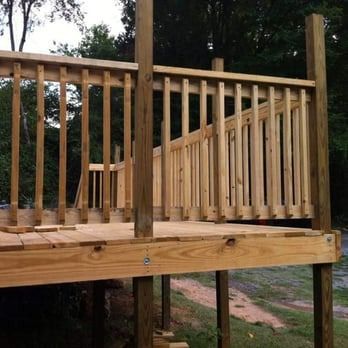A wooden deck with a railing is being built in the woods.