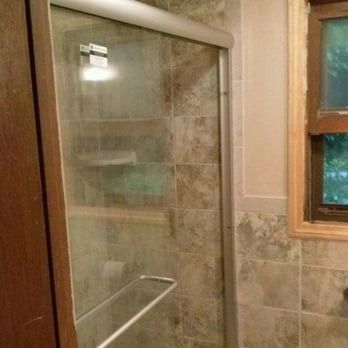 A bathroom with a sliding glass shower door and a window.