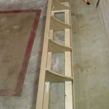 A wooden shelf is sitting on a concrete floor next to a rug.