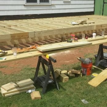 A wooden deck is being built in the grass in front of a house.