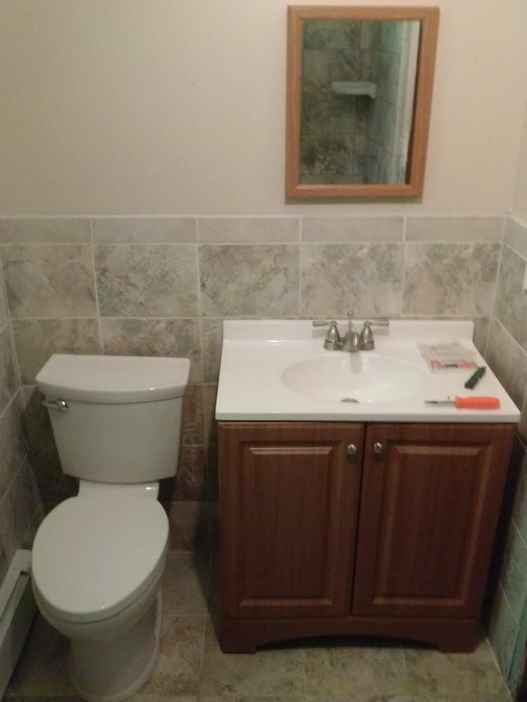 A bathroom with a toilet , sink and mirror.