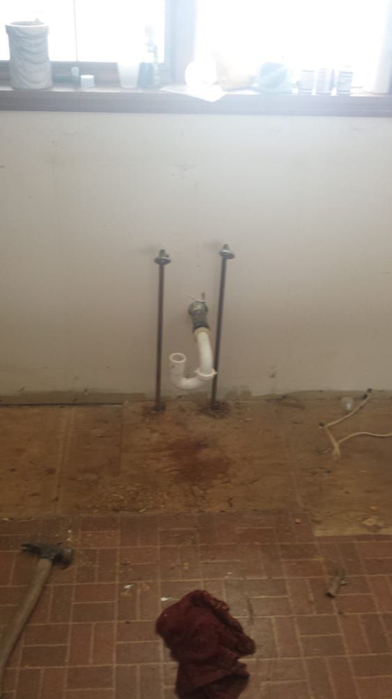 A bathroom with a sink and a window and a towel on the floor.